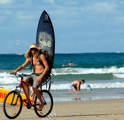 surfer-with-surf-board-on-back-of-his-bike-on-byron-bay-main-beach-CNF7BC.jpg